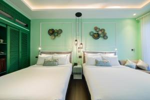 会安Lavini Hoian Boutique Villa的绿墙客房内的两张床