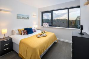 圣奥尔本斯St Albans City Apartments - Near Luton Airport and Harry Potter World的一间卧室配有一张带黄色毯子和窗户的床