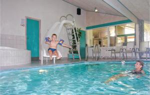 伦斯楚普Awesome Home In Lkken With Indoor Swimming Pool的坐在游泳池水滑梯上的男孩