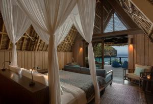 Tanjung Ringgit捷瓦贝罗亚马海滩营地酒店的一间卧室设有一张天蓬床,享有海景