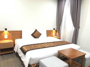 富国Nakichi Hotel Phú Quốc的酒店客房配有一张床铺和一张桌子。