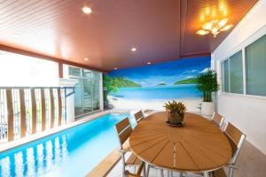 芭东海滩Rudi House的一间带游泳池、桌子和椅子的用餐室