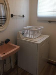 CanoraCozy Cottage的一间带水槽的浴室和一台洗衣机内的洗衣篮