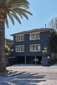 悉尼Ballantyne at Mosman Apartments的一座黑色的建筑,前面有棕榈树