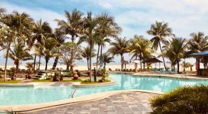 瓜拉丁加奴报春花海滩酒店的度假村内一座种有棕榈树的大型游泳池