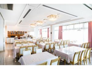 泉佐野丰荣酒店的一间设有白色桌椅的用餐室