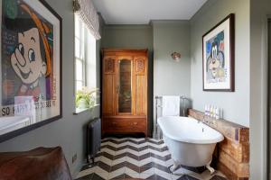布莱顿霍夫布莱顿艺术家驻地公寓的一间带白色浴缸和 ⁇ 格地板的浴室