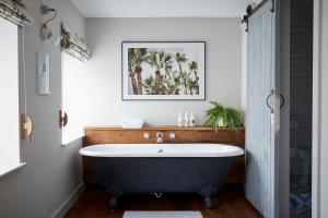 彭赞斯康沃尔艺术家酒店的带浴缸的浴室,墙上挂着一幅画