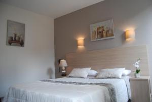 罗德兹Logis Hôtel du Midi - Rodez Centre-Ville的卧室配有白色床,墙上有两盏灯