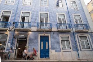 里斯本Lisbon Alfama Tagus的一座蓝色的建筑,前面的人坐在