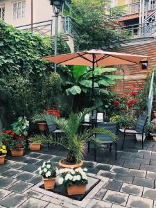 第比利斯Apartment Botanikuri 15的天井配有带雨伞和植物的桌子