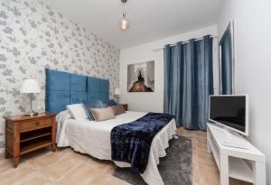 宏达海滩Luxury Suite Sea Front的一间卧室配有一张带蓝色床头板的床和一台电视