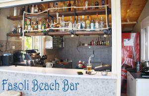 帕拉利亚潘塔利莫诺斯法索里一室公寓的海滩酒吧设有墙上装有瓶子的吧台