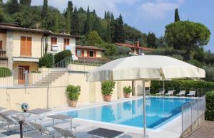 加尔多内-里维耶拉Villa Belvedere的一个带遮阳伞和椅子的游泳池以及一座房子
