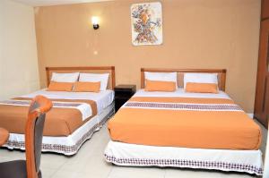 日惹玛塔拉姆马里保罗酒店的一间卧室配有两张带橙色和白色床单的床