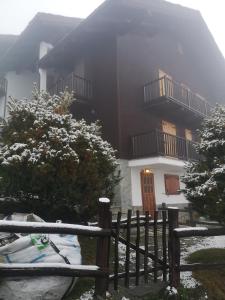 沙穆瓦Casetta Chamois的雪中的房子,前面有栅栏