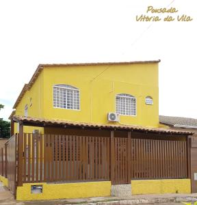 巴西利亚Pousada Vitória da Vila的前面有木栅栏的黄色房子
