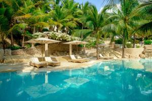 迪亚尼海滩斯瓦希里海滩度假村的一个带椅子和遮阳伞的游泳池以及棕榈树