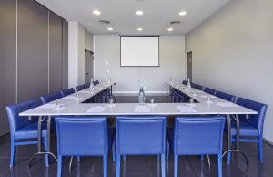 阿尔弗拉基德里斯本阿尔弗拉基德智选假日酒店的一间会议室,配有大桌子和蓝色椅子