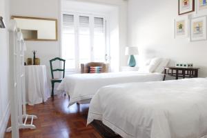 里斯本马格诺利娅住宿加早餐旅馆的配有白色墙壁和木地板的客房内的两张床