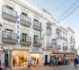 内尔哈Hostal Luna de Nerja的带阳台的白色建筑和商店