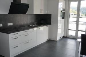 诺伊恩比尔格Ferienwohnung Schauinsland的厨房配有白色橱柜和黑色台面