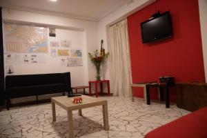 圣保罗Hostel Calábria na Vila Madalena junto a alegria da Vila的一间客厅,在红色的墙上配有电视