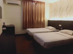 拿笃Fajar Hotel的酒店客房设有两张床和窗户。