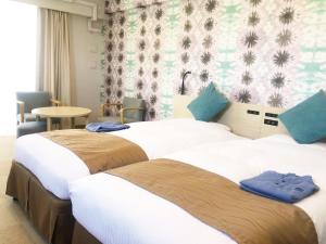 北谷町冲绳北谷柔婕阁酒店的两张位于酒店客房的床,上面有蓝色的毛巾