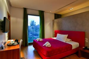 莱切莱切艺术和公园酒店的一间卧室配有红色的床、一张书桌和一个窗户。