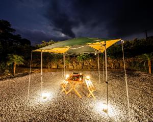 今归仁村Okinawa BBQ Glamping的夜间帐篷下的野餐桌