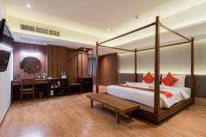 曼谷True Siam Phayathai Hotel的一间卧室配有一张天蓬床、一张桌子和一张桌子