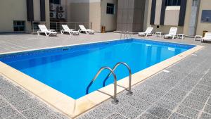 多哈Al Muntazah Plaza Hotel的一个带椅子和桌子的大型游泳池