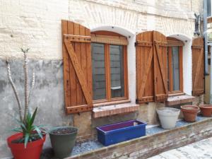 迪耶普le petit dieppois的一座拥有木制百叶窗和盆栽植物的建筑