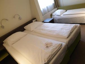 纽伦堡纽伦堡贝林尔斯城市酒店的配有白色床单的酒店客房内的两张床