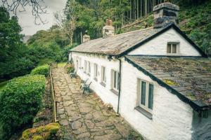 卡纳芬CELYN - SNOWDONIA COTTAGE的一座白色的建筑,位于房子旁边的石头路上