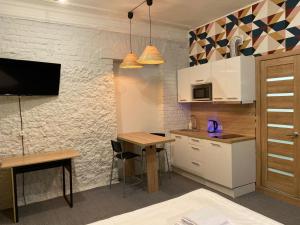 莫斯科Axel Apart Hotel Moscow的厨房配有白色橱柜、桌子和电视。