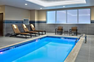 大急流城Hyatt Place Grand Rapids Downtown的游泳池位于酒店客房内,配有椅子和桌子