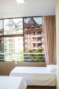 皮拉图巴Pousada Center的酒店客房设有两张床和大窗户。
