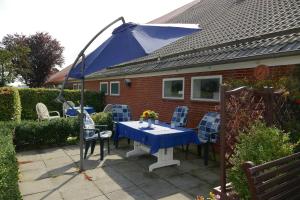 JemgumFerienhof van Vlyten_ 45006的房屋前的一张桌子和椅子,上面有一把蓝色雨伞