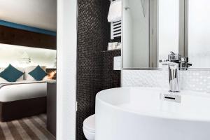 巴黎最佳西方努维尔奥尔良蒙帕纳斯酒店的一间带水槽的浴室和一间带一张床的卧室