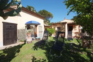 里奥内莱尔巴La Villetta Isola d'elba-ortano 10的一个带椅子和遮阳伞的庭院和一座房子