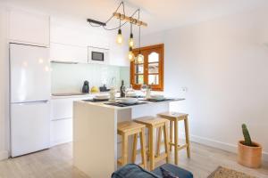 阿雷西费Vela的一间厨房,配有白色橱柜和一个带凳子的厨房岛