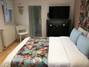 兰斯La Petite Maison de Jane的一间卧室配有一张带花卉毯子的床