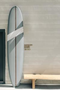 马里布马布里冲浪者酒店的靠在长凳旁边的墙上的冲浪板