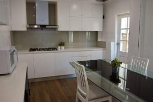 悉尼Carnarvon Lodge Kirribilli, Sydney的厨房配有白色橱柜和玻璃桌