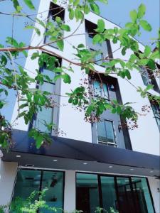 乌隆他尼Tisa Hotel Udonthani的前方有窗户和树木的建筑