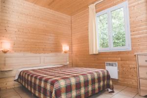 蒙科坦特Terres de France - Natura Resort Pescalis的木制客房内的一间卧室,配有一张床