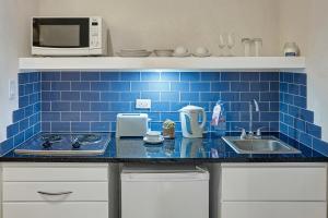 基督教堂市巴特弗莱海滩酒店的厨房设有水槽和蓝色瓷砖墙。