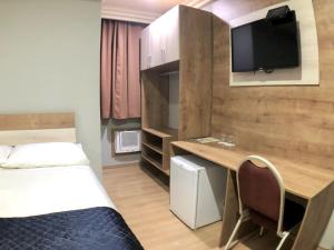 库里提巴特拉萨斯酒店的小房间设有一张床和一张书桌及电视